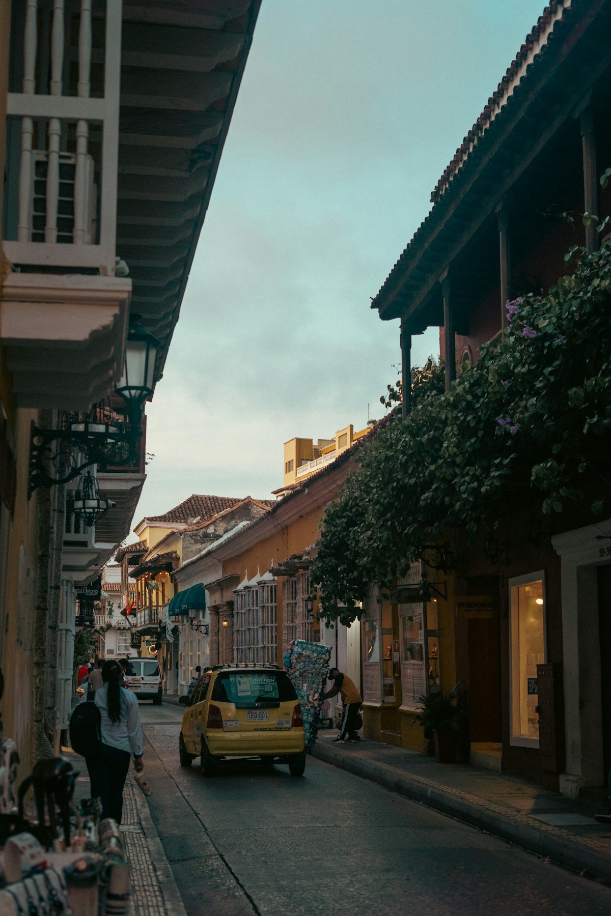 Historic cobblestone street with colonial balconies and yellow taxi, Cartagena old town