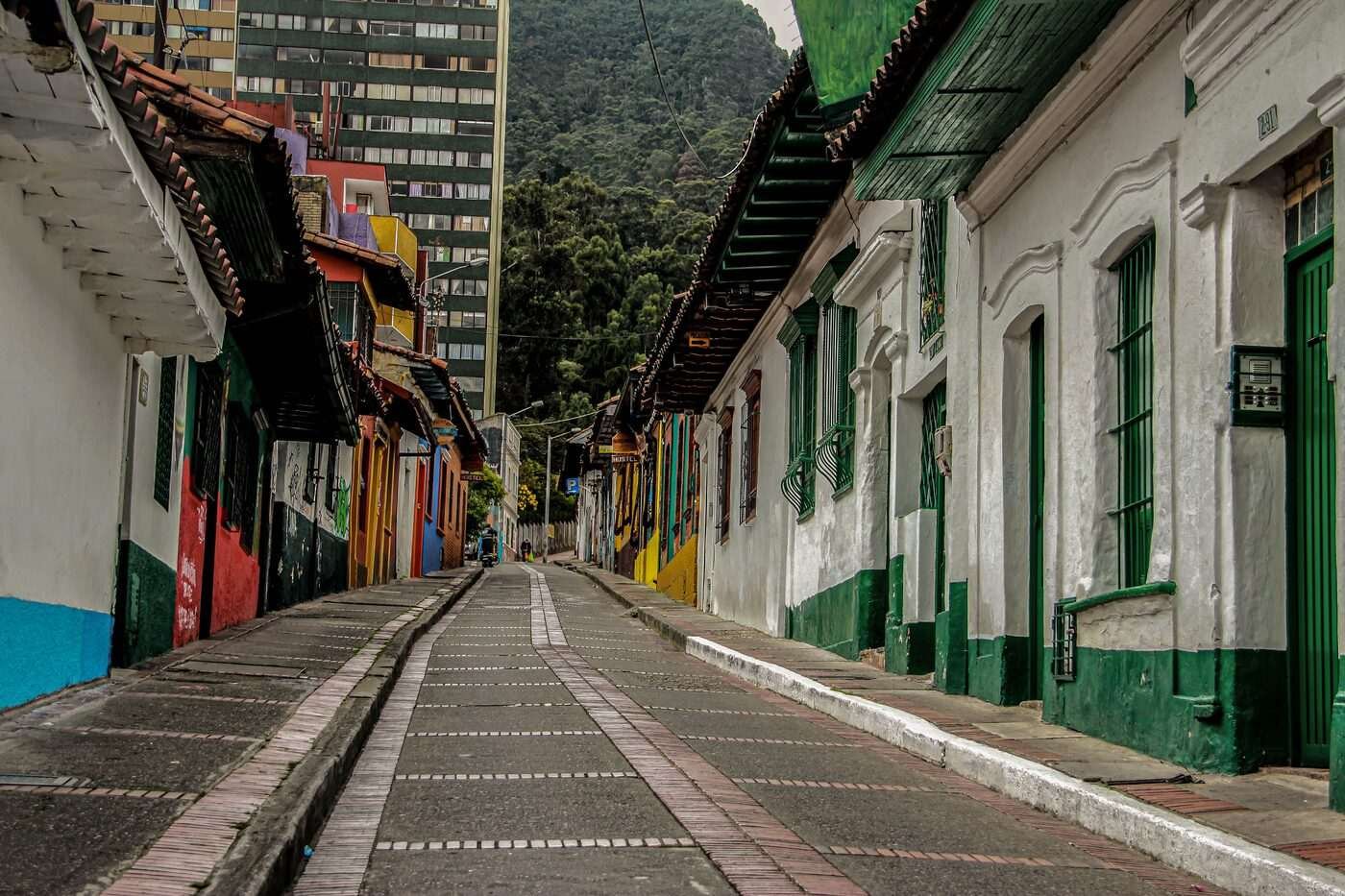 Colourful traditional houses lining a quiet street in La Candelaria, Bogotá, with mountains behind
