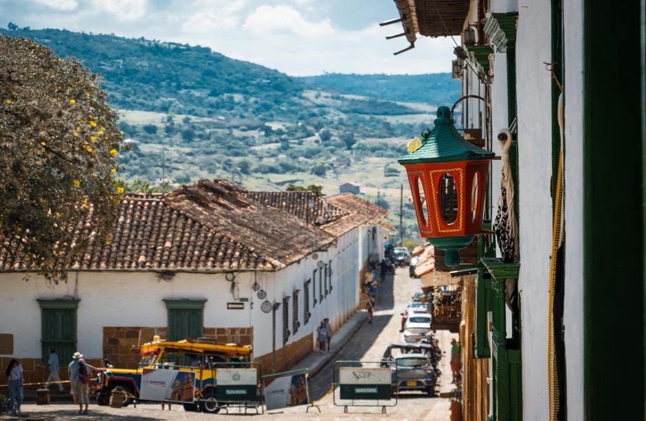 Street view of Barichara with colorful street lamp and cobblestone road leading toward the hills