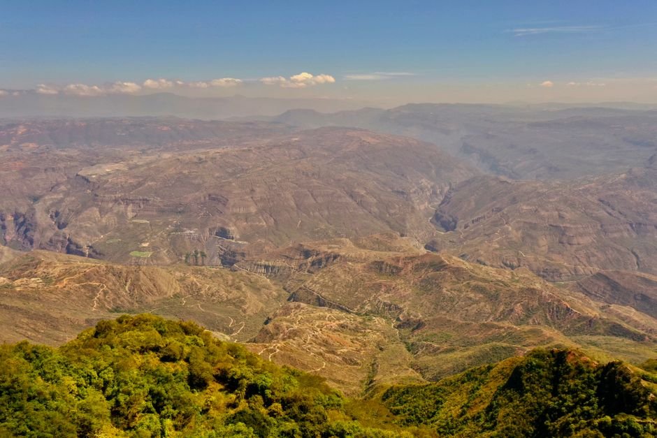 Aerial view of Chicamocha Canyon near Bucaramanga, deep ochre-coloured gorge with paragliders visible against a blue sky
