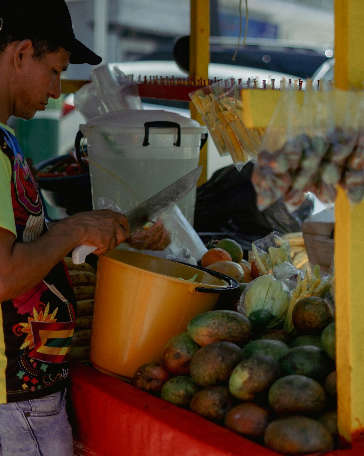 Vendor preparing fresh tropical fruit at a colourful street food stand in Cali, Colombia