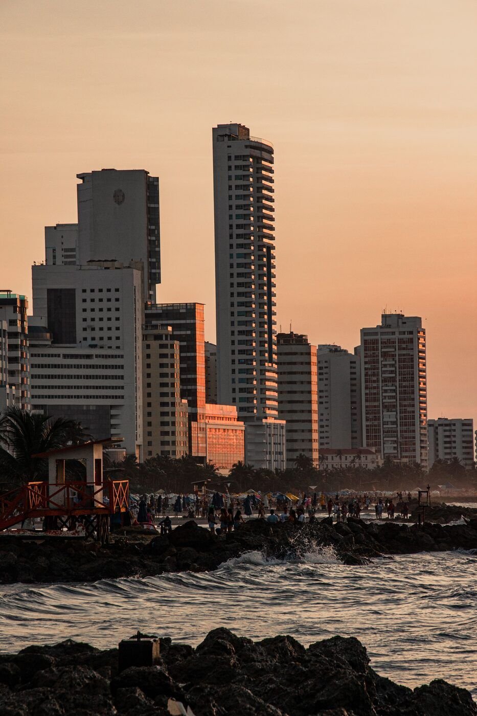Cartagena beach at sunset with modern skyline silhouetted against golden sky, Colombia