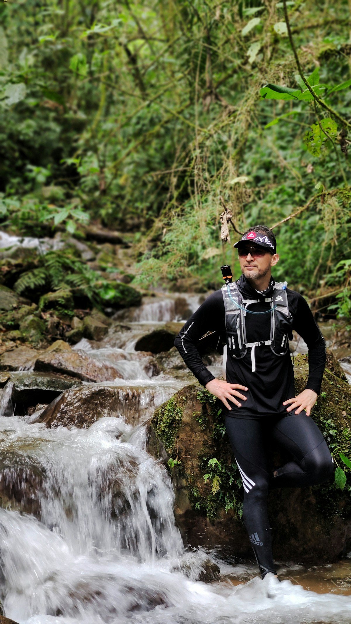 Adventure trail runner standing next to a mountain stream in the Colombian Andes