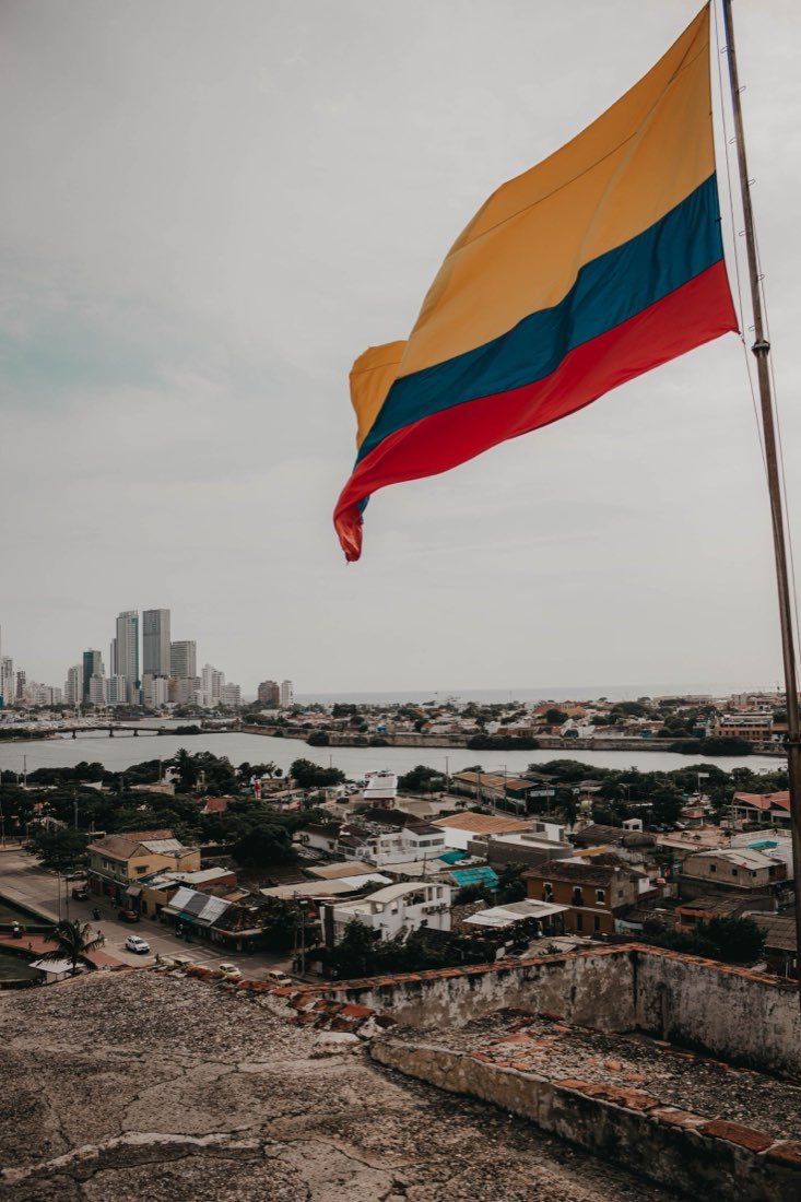 Colombian flag flying over the Cartagena skyline from a fortress wall