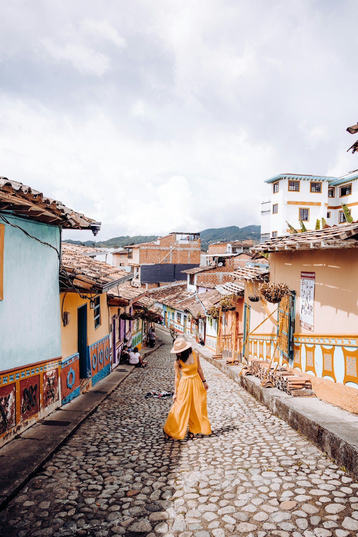 Woman in yellow dress walking cobblestone streets of Guatapé, Colombia