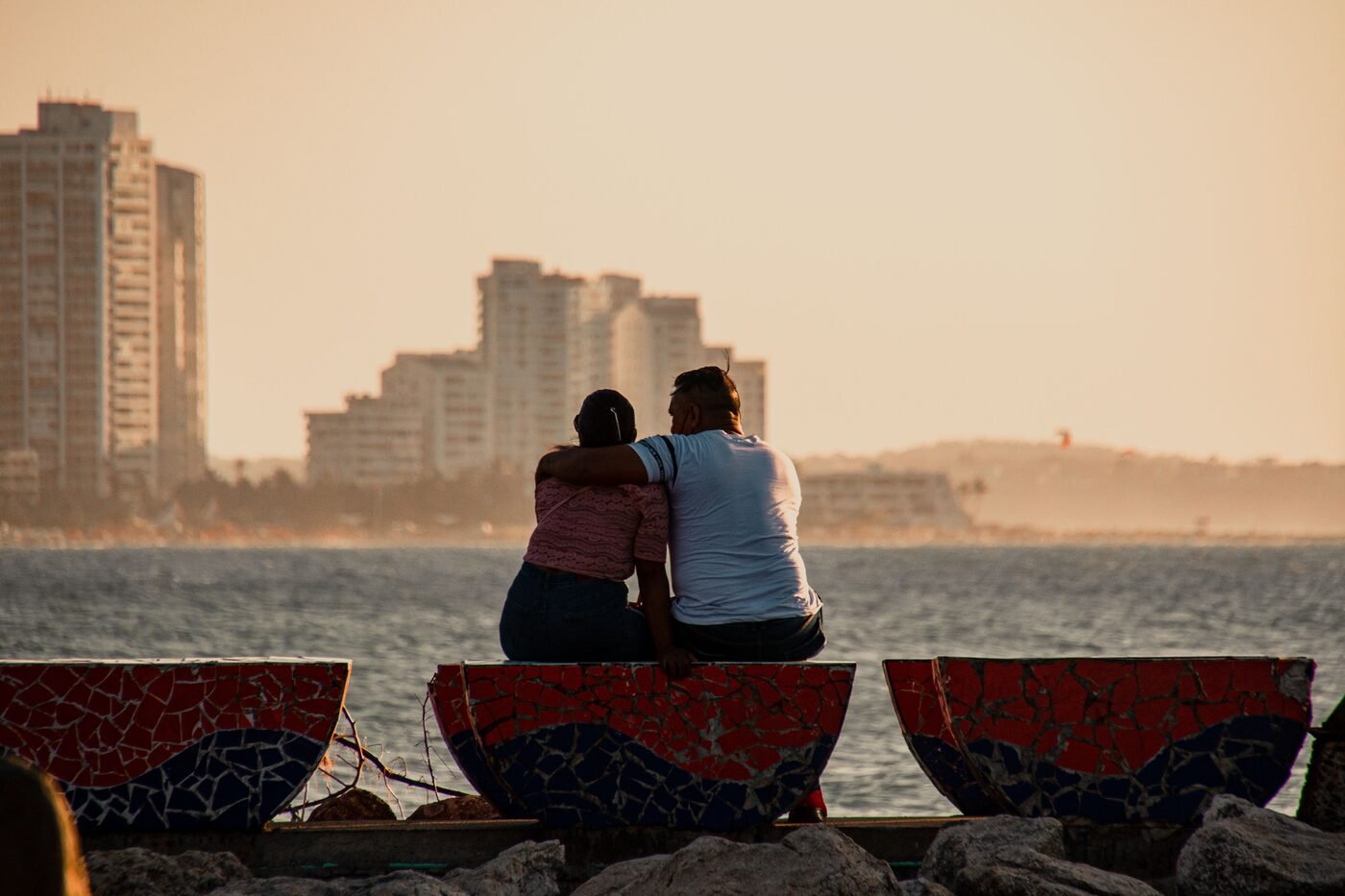 Couple sitting together at sunset on Cartagena waterfront with the city skyline behind them
