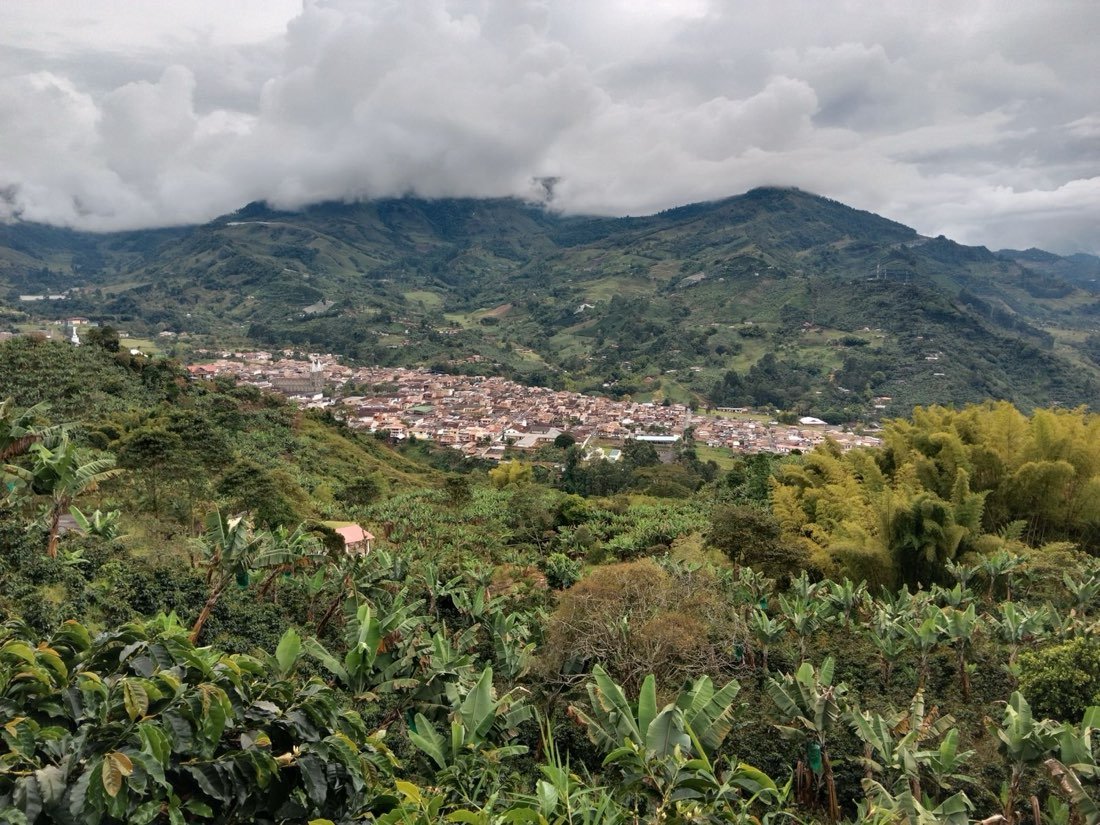 Town of Jardin among green coffee hills under low cloud, Antioquia, Colombia