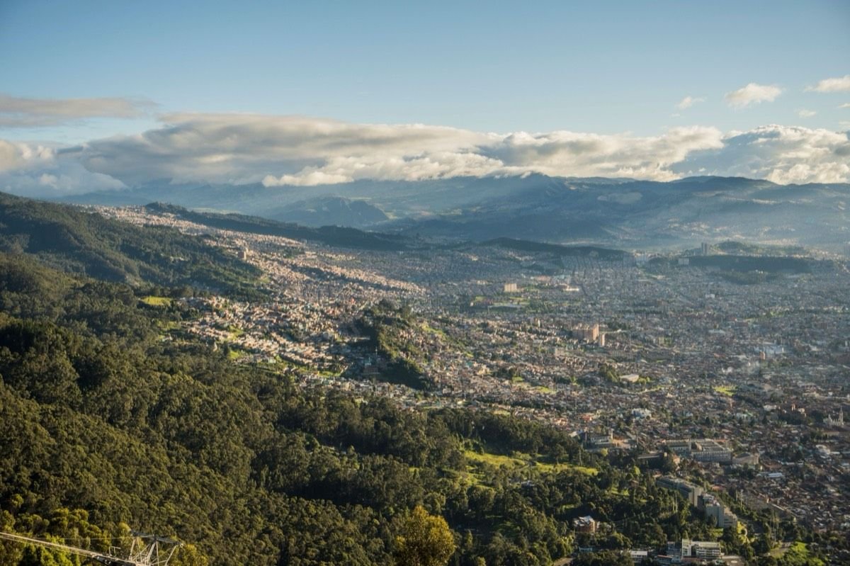 Aerial view of a Colombian city nestled in the Andes mountains under a blue sky