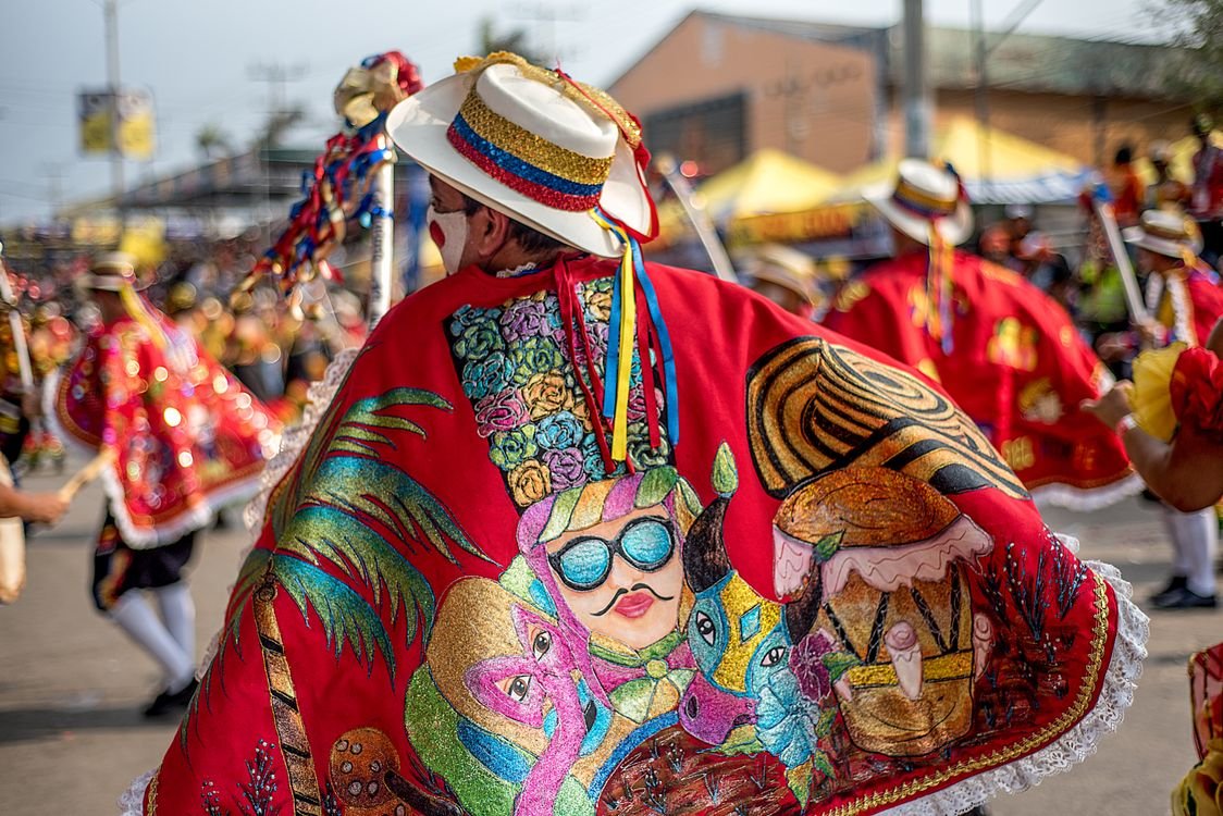 Colombian dancer in embroidered red cape at a traditional folklore parade