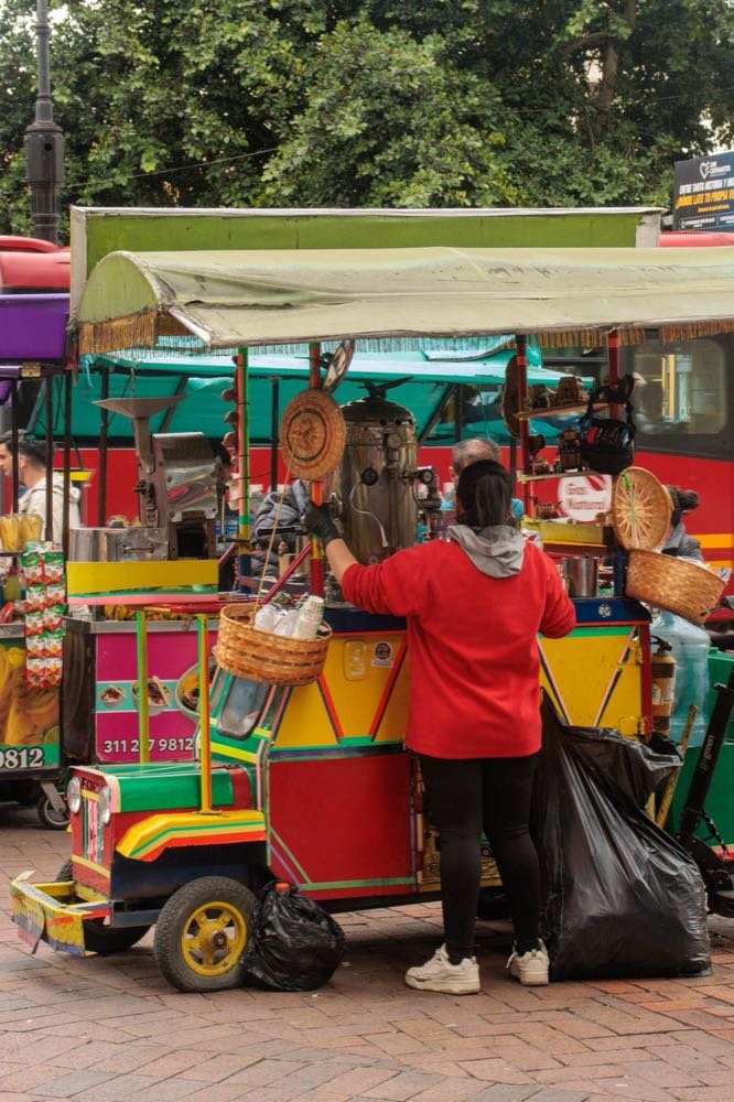 Colourful street food cart and vendor on a pavement in Bogotá, Colombia