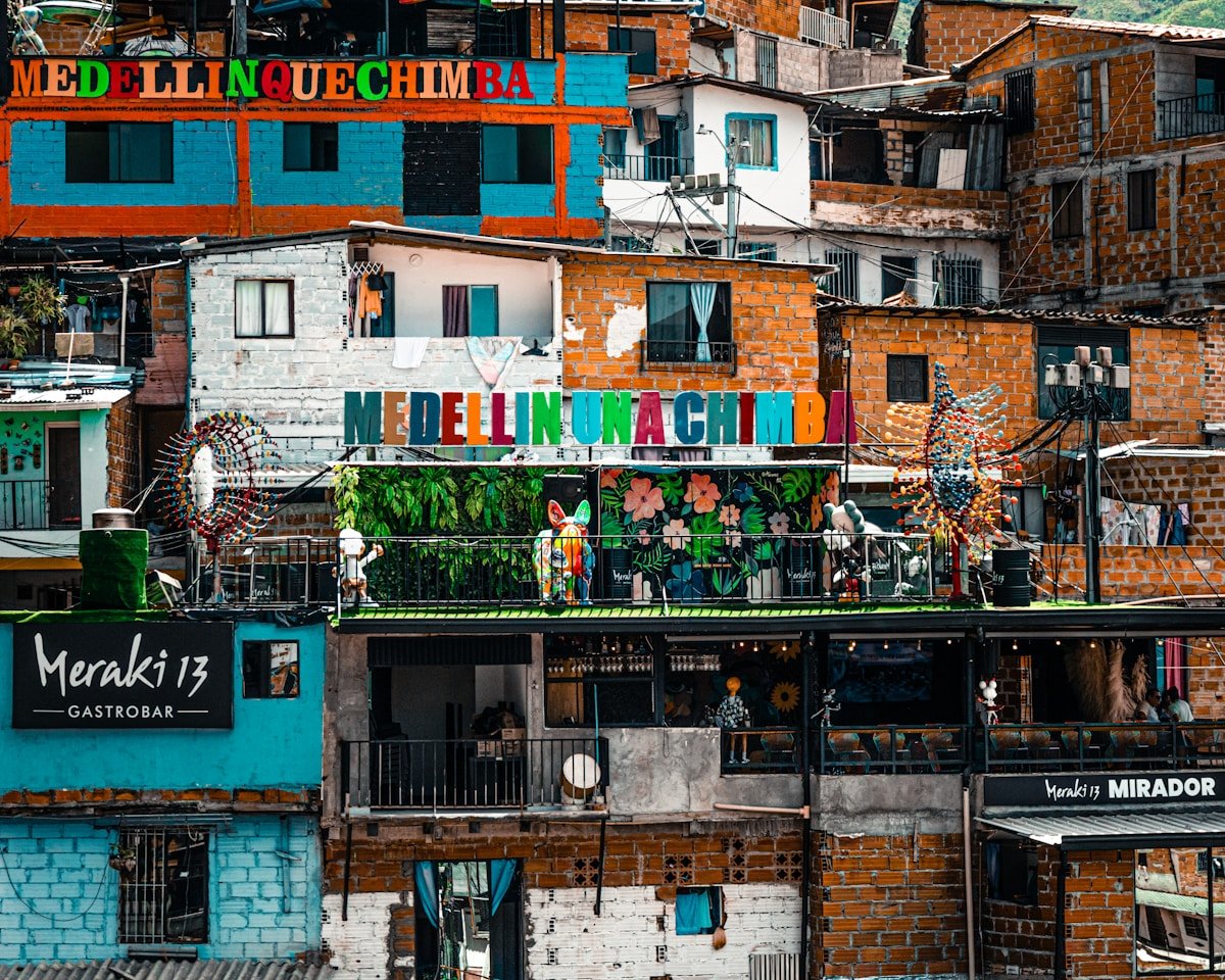 Colourful painted buildings in Medellin's Commune 13 with the Meraki 13 Gastrobar sign visible on an upper terrace
