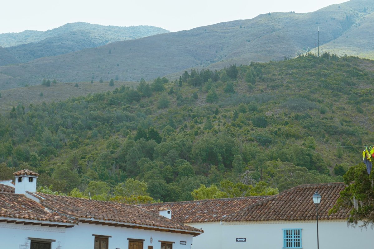 White colonial buildings with terracotta tiled roofs and green mountains rising behind Villa de Leyva, Colombia