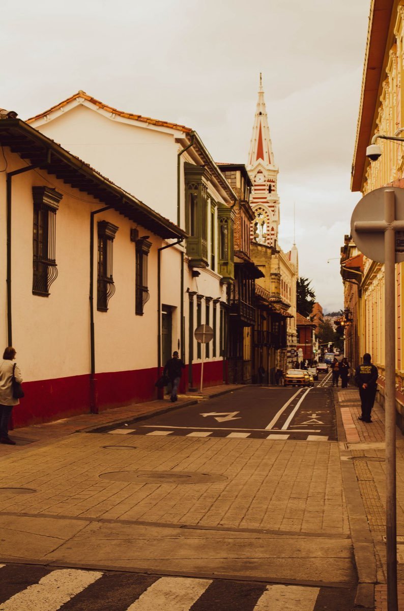 Narrow street in Bogota historic centre with a church tower in the distance