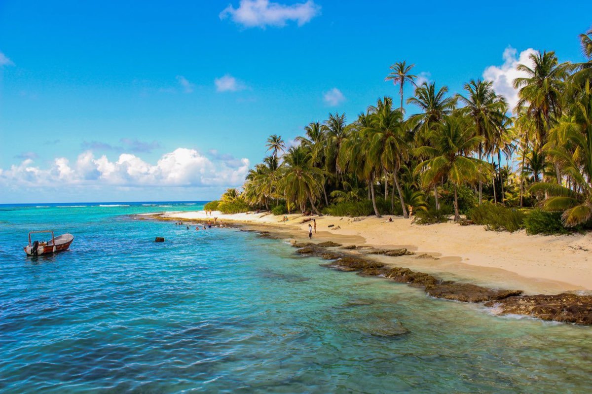 Palm-fringed beach and turquoise water with a boat on San Andres island