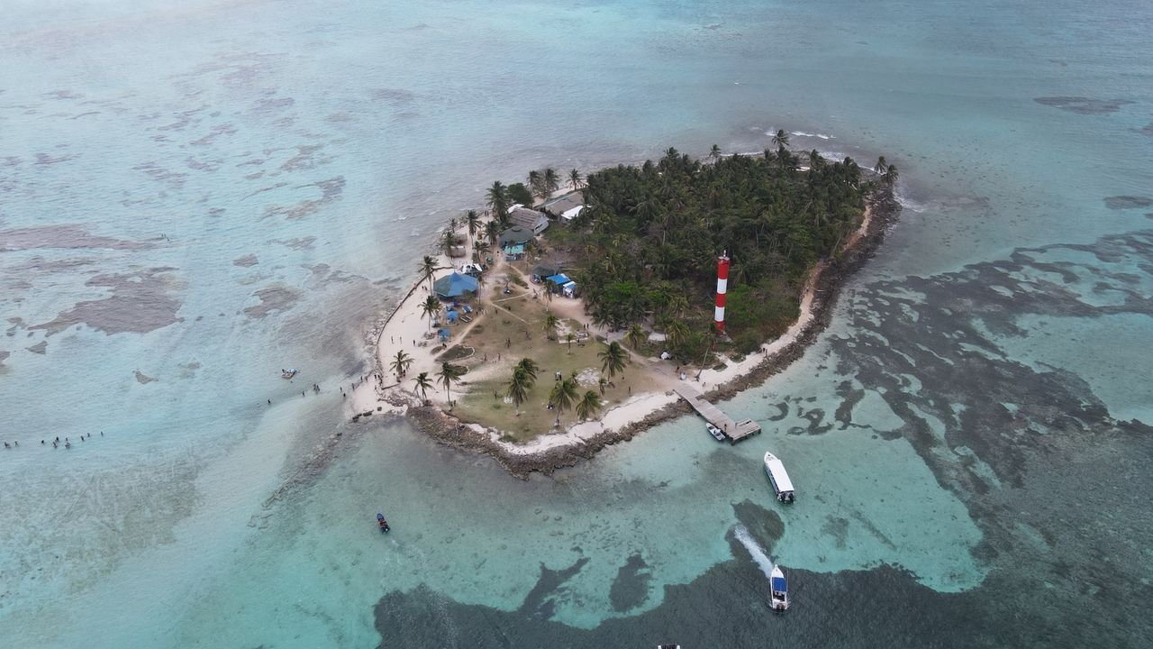 Aerial view of a small cay with a red and white lighthouse near San Andres