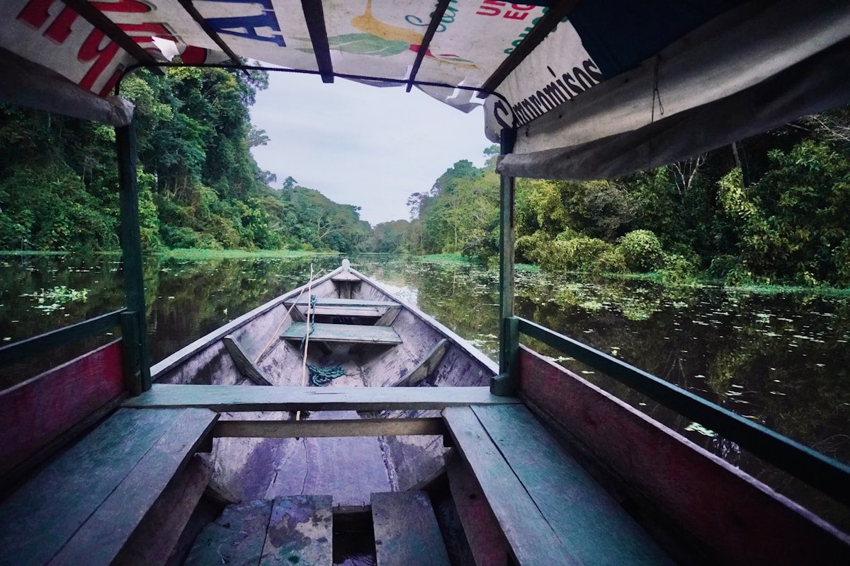 Wooden canoe navigating through lush Amazon jungle waterway near Puerto Nariño, Colombia