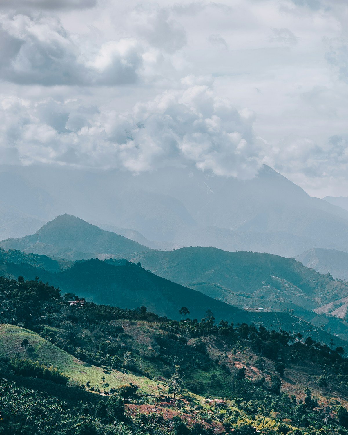 Green layered mountain ridges with scattered farms and clouds above the Jardín valley, Antioquia, Colombia
