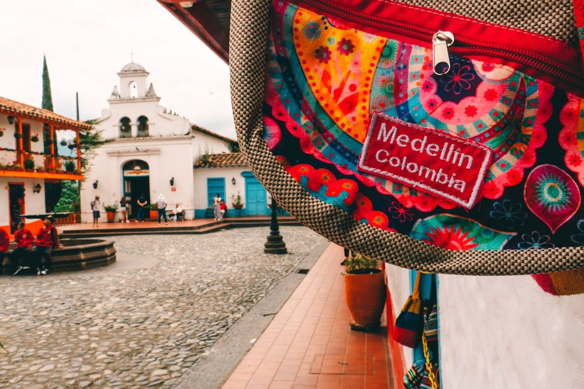 Colourful Medellin Colombia bag in front of a colonial plaza with a white church