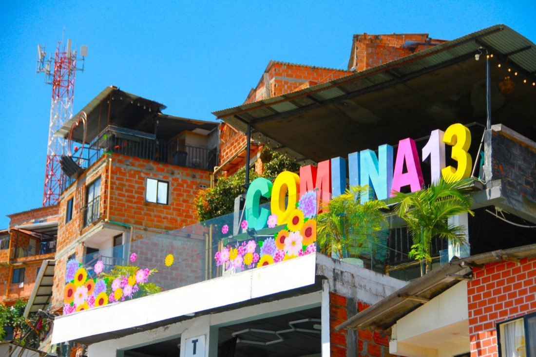 Colourful Comuna 13 sign and flower murals on a brick terrace in Medellin, Colombia