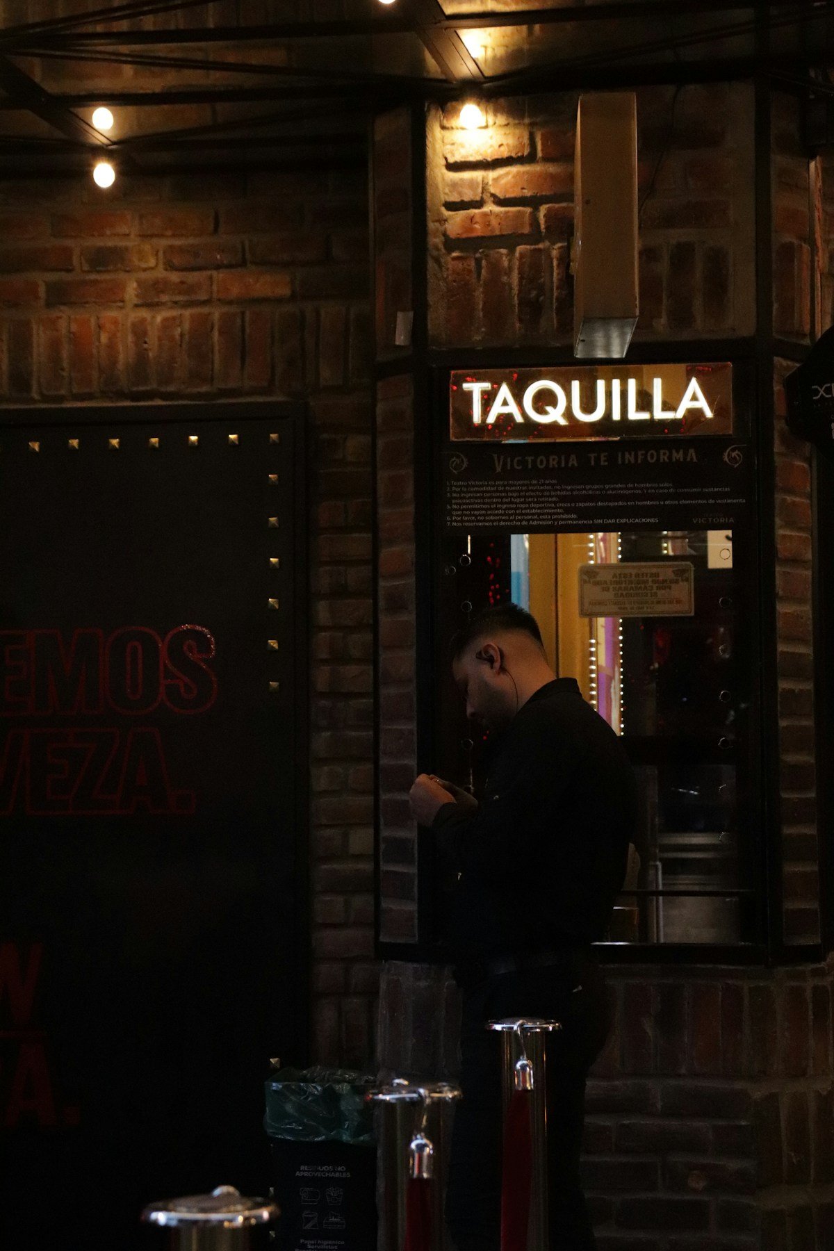 A man standing outside a restaurant at night in Medellin, Colombia, with warm lights behind him