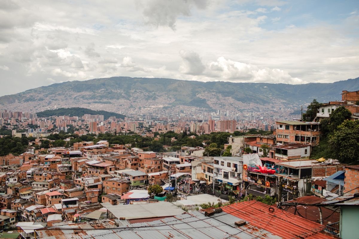 Brick rooftops of a Medellín hillside barrio with the city and mountains beyond