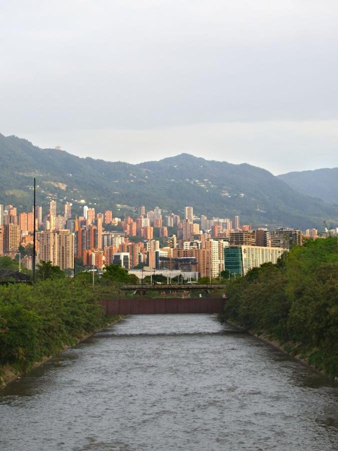 Medellín high-rises beyond the Medellín River with green Andean slopes behind