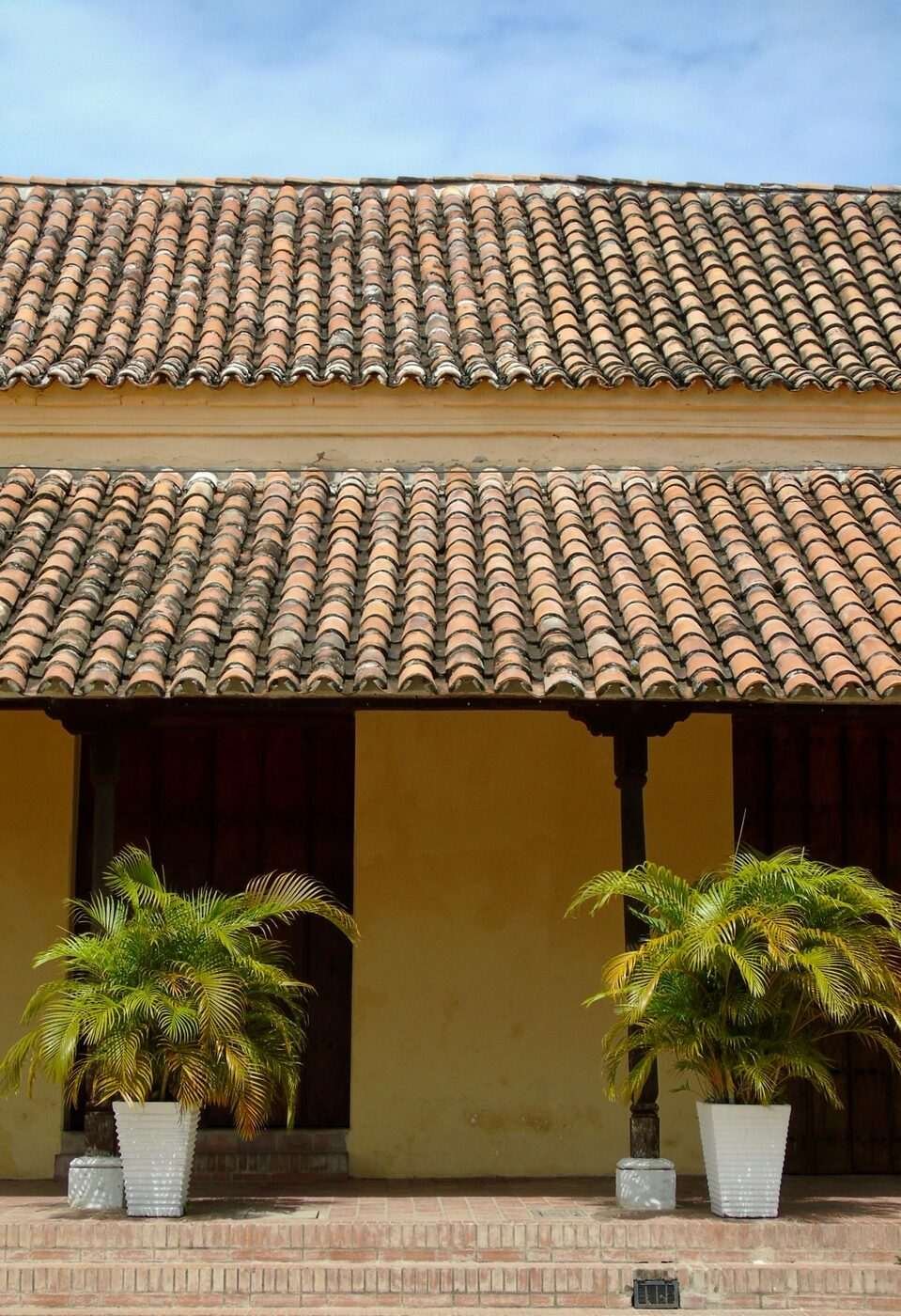 Colonial building with terracotta-tiled roof and palm plants in courtyard, Mompox, Colombia