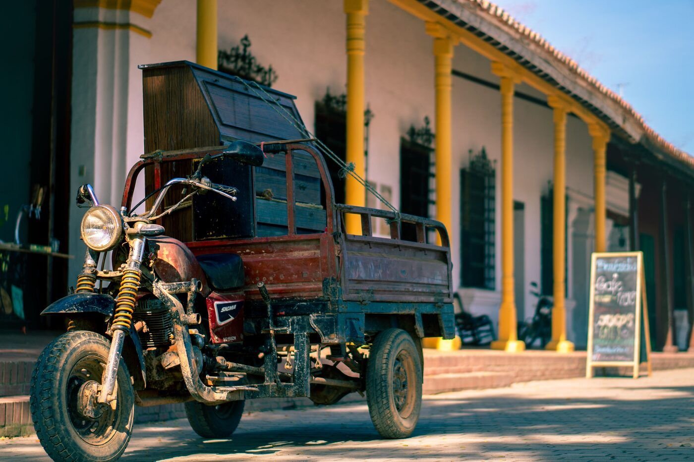Rustic motorized trike parked before a yellow colonial colonnade in Santa Cruz de Mompox, Colombia