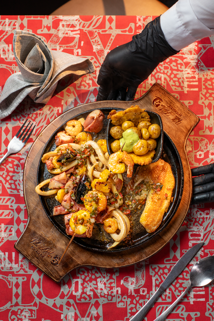 Traditional Caucano food spread at a Popayán restaurant — empanadas, lechona, and chontaduro on wooden board