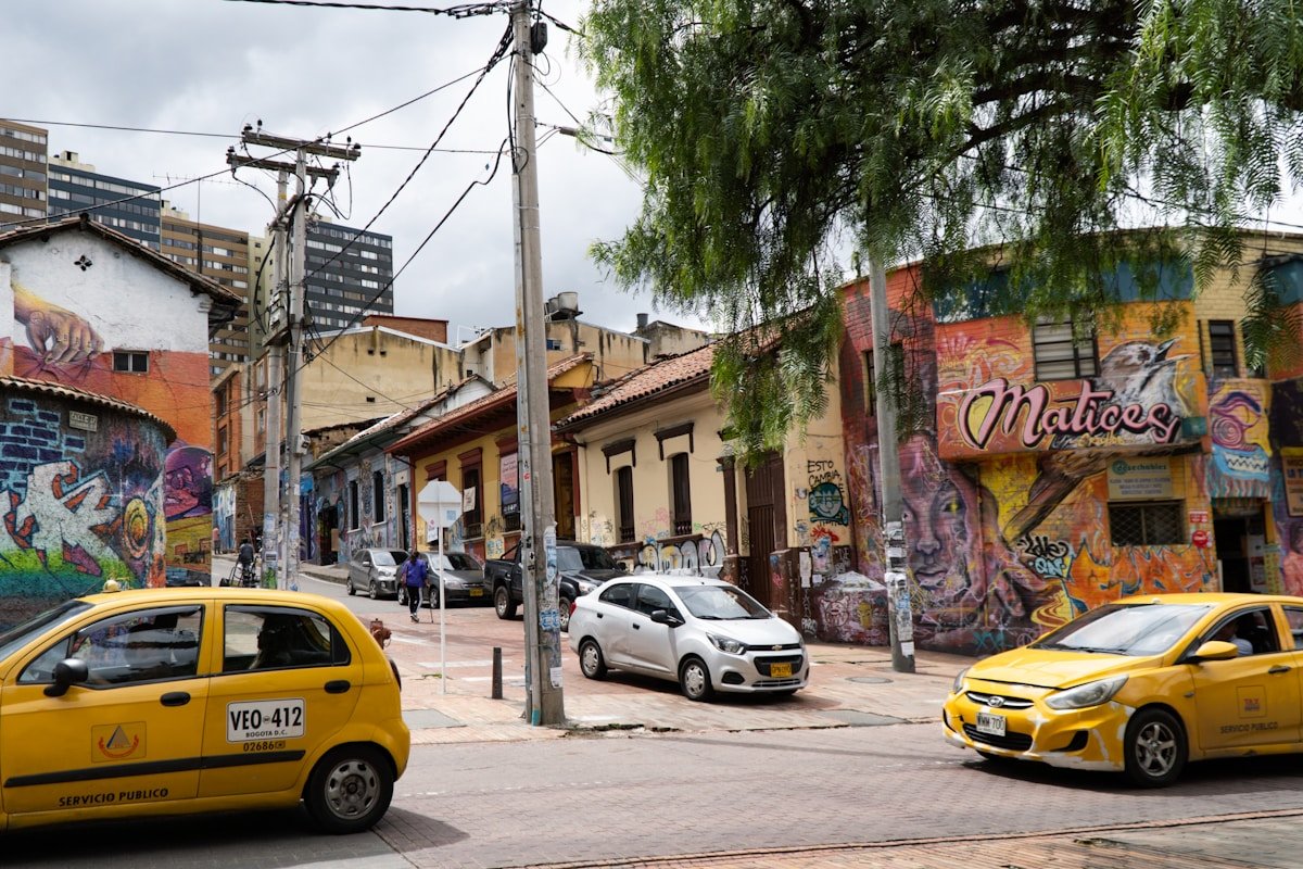 Yellow taxis on a Bogota street lined with colourful street murals, Colombia