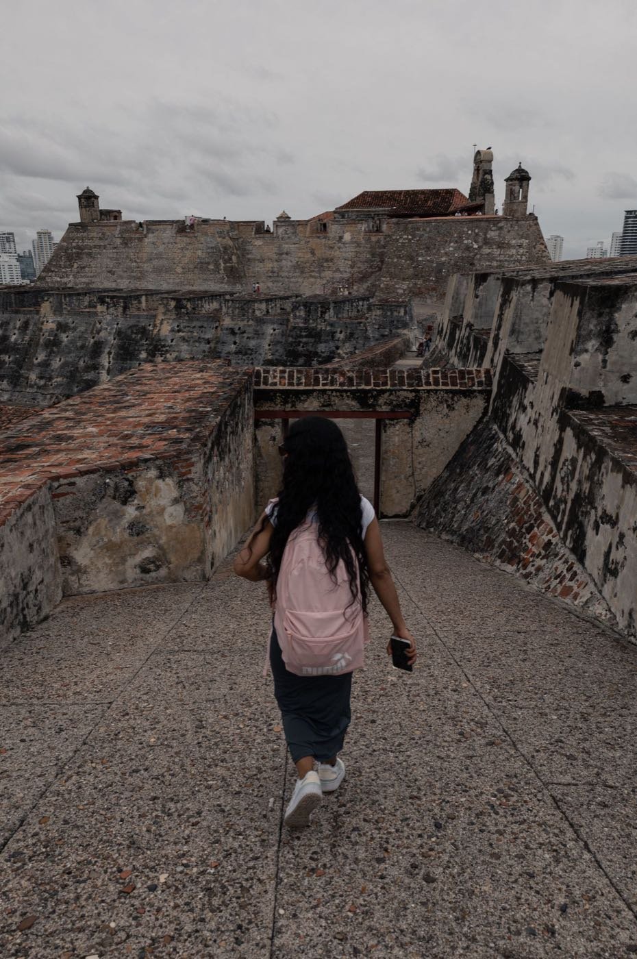 Visitor with a backpack walking the stone ramparts of Castillo San Felipe de Barajas in Cartagena, Colombia