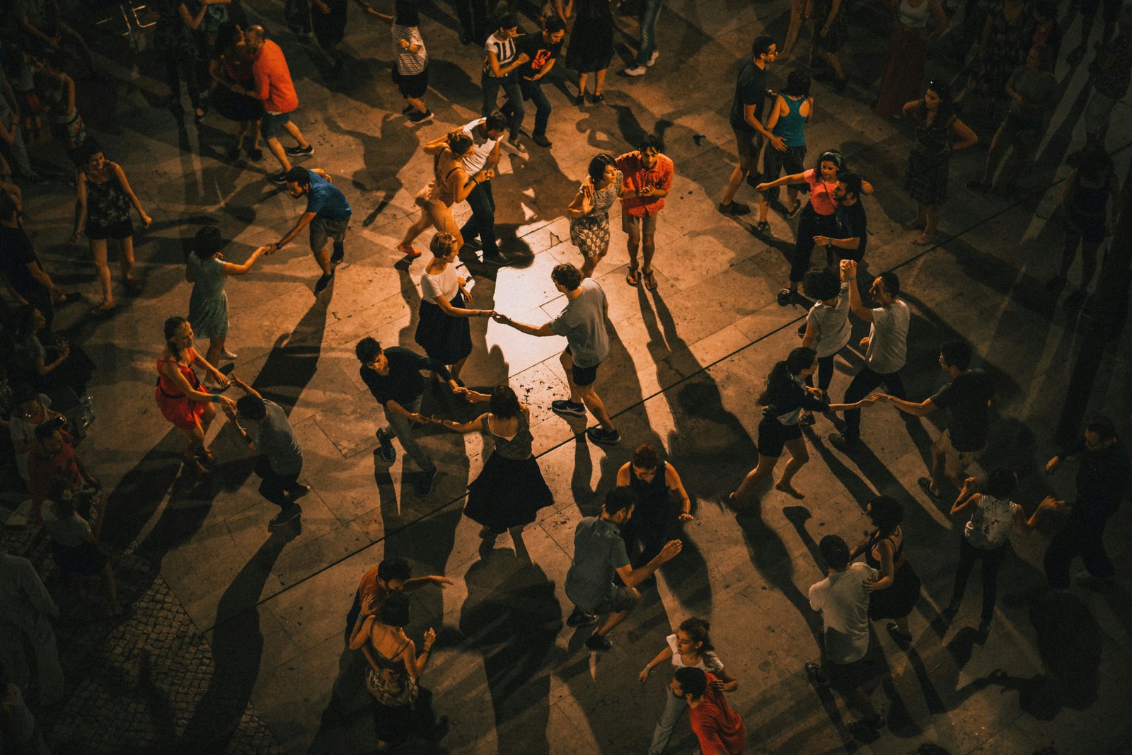 Latin salsa dance couple in elegant white costumes performing against a black studio backdrop
