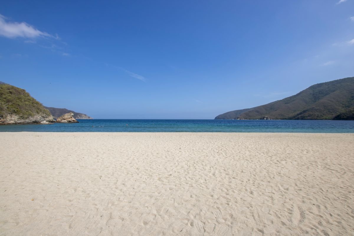 Empty white-sand bay with blue sea and green headlands near Tayrona, Santa Marta