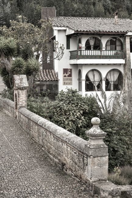 Hacienda-style hotel courtyard in Villa de Leyva with colonial whitewashed walls and a garden with rose bushes
